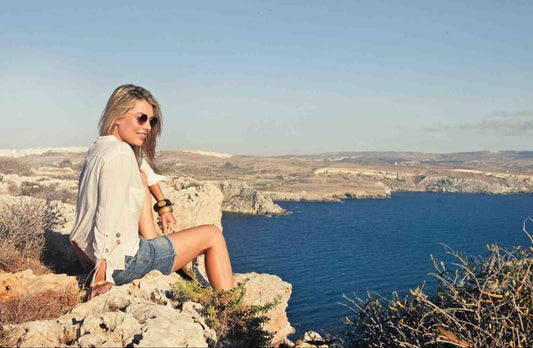 Woman wearing sunglasses sitting on a cliff